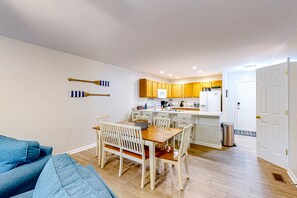 Un espace de vie compact comprenant un coin repas, une cuisine et une porte donnant sur une autre pièce.