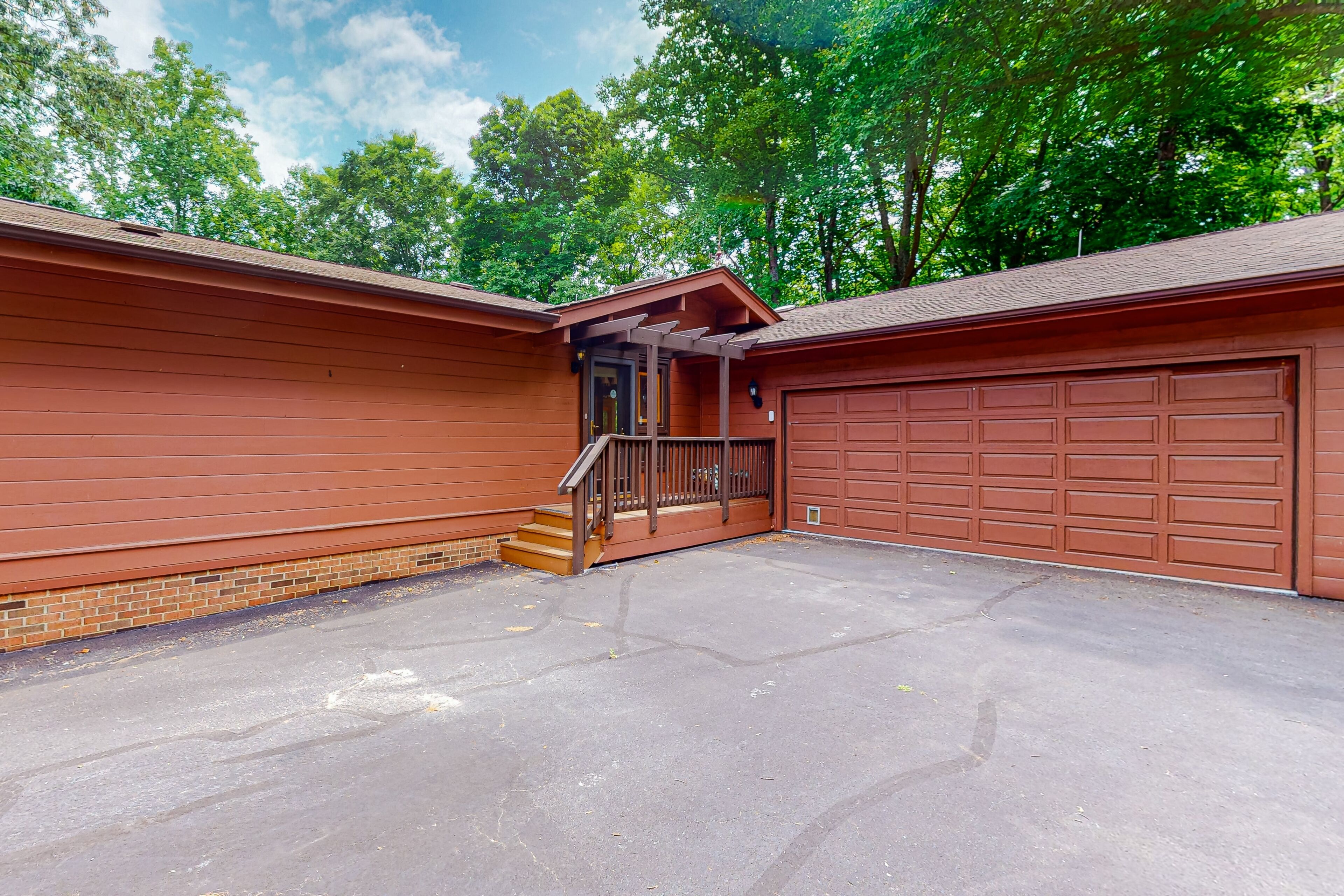 A garage with a brown exterior, a small set of steps leading to a door, and a clear sky in the background.