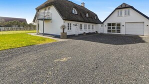 A two-story house with a balcony, a garage, and a gravel driveway. - 4 Star Holiday Home in Blokhus (Blokhus)