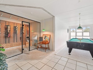 A room with a pool table, a wine rack, and a painting on easel. - 4 Star Holiday Home in Blokhus (Blokhus)