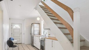 A kitchen with a stove, refrigerator, and wooden staircase. - 4 Star Holiday Home in Blokhus (Blokhus)