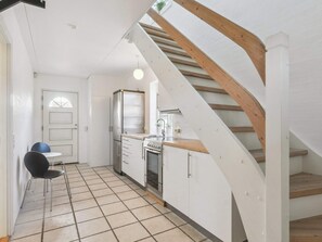 Eine Küche mit Herd, Kühlschrank und einer Holztreppe.