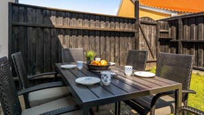 Ein Holztisch mit Stühlen, eine Fruchtkorb und Teller und Tassen.