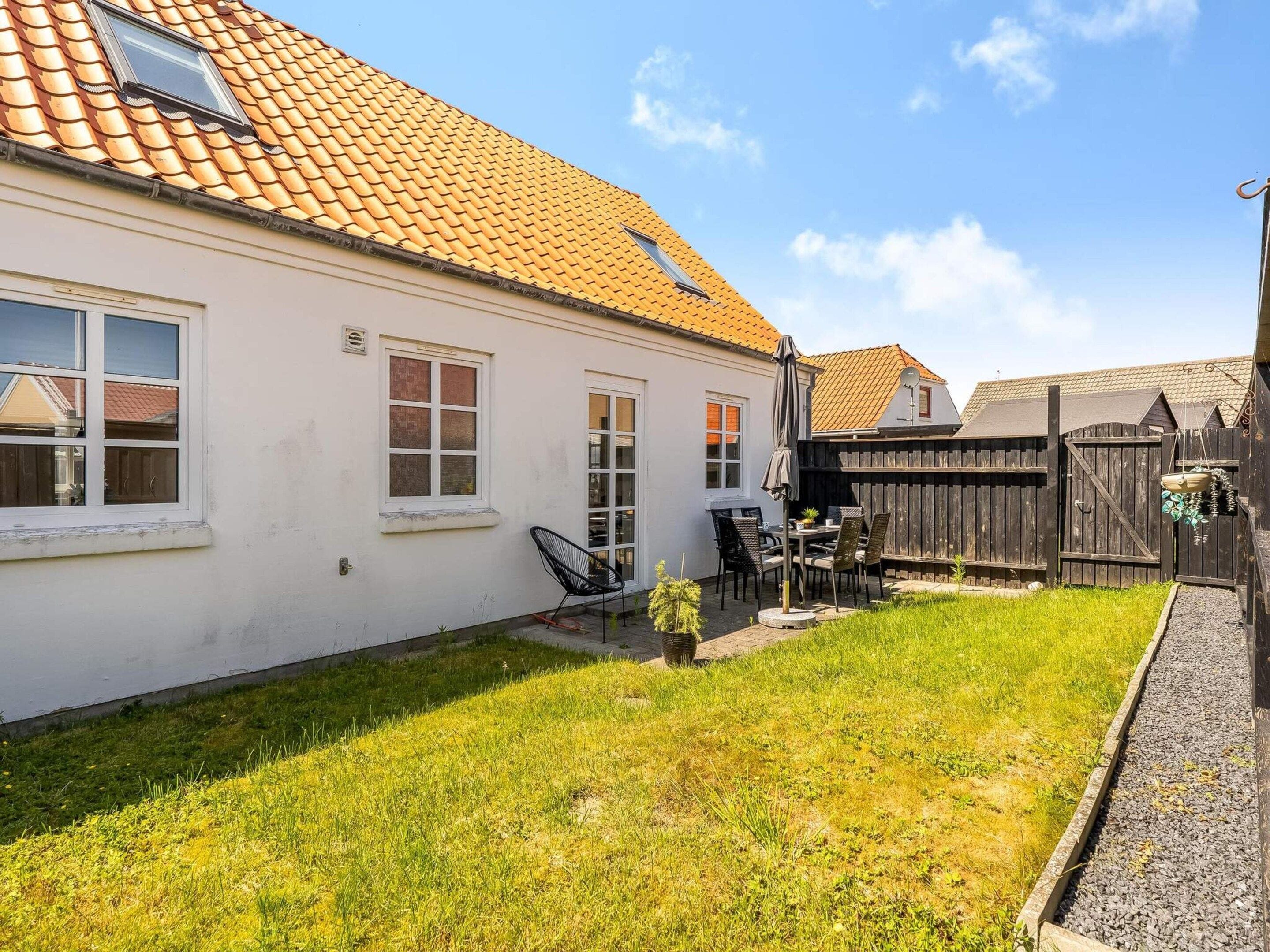 A residential property with a white exterior, a tiled roof, and a fenced backyard.