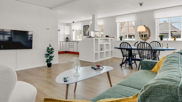 Ein modernes Wohnzimmer mit einer Couch, einem Couchtisch und einem Essbereich mit Stühlen und einem Tisch.