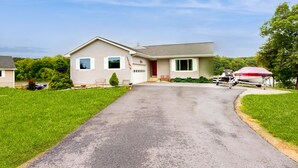 A two-story house with a front driveway, a covered boat trailer, and a well-maintained lawn. - Spacious lakefront house w/patio, balcony, grill & foosball (Mineral)