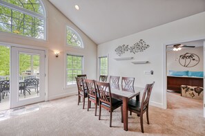 A dining area with a large table and chairs, a ceiling fan, and a view of the outdoors through large windows. - Sprawling waterfront home with kayaks, game room, and hot tub (Mineral)