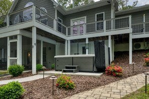 A two-story house with a covered patio, a hot tub, and a landscaped garden. - Sprawling waterfront home with kayaks, game room, and hot tub (Mineral)