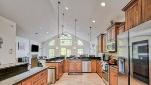 A spacious kitchen with wooden cabinets, stainless steel appliances, and large windows. - Sprawling waterfront home with kayaks, game room, and hot tub (Mineral)