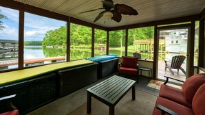 A covered outdoor area with a table, chairs, and a view of a lake and dock. - Sprawling waterfront home with kayaks, game room, and hot tub (Mineral)