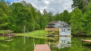 A lakeside property with a dock, a covered deck, and a house with a second level. - Sprawling waterfront home with kayaks, game room, and hot tub (Mineral)