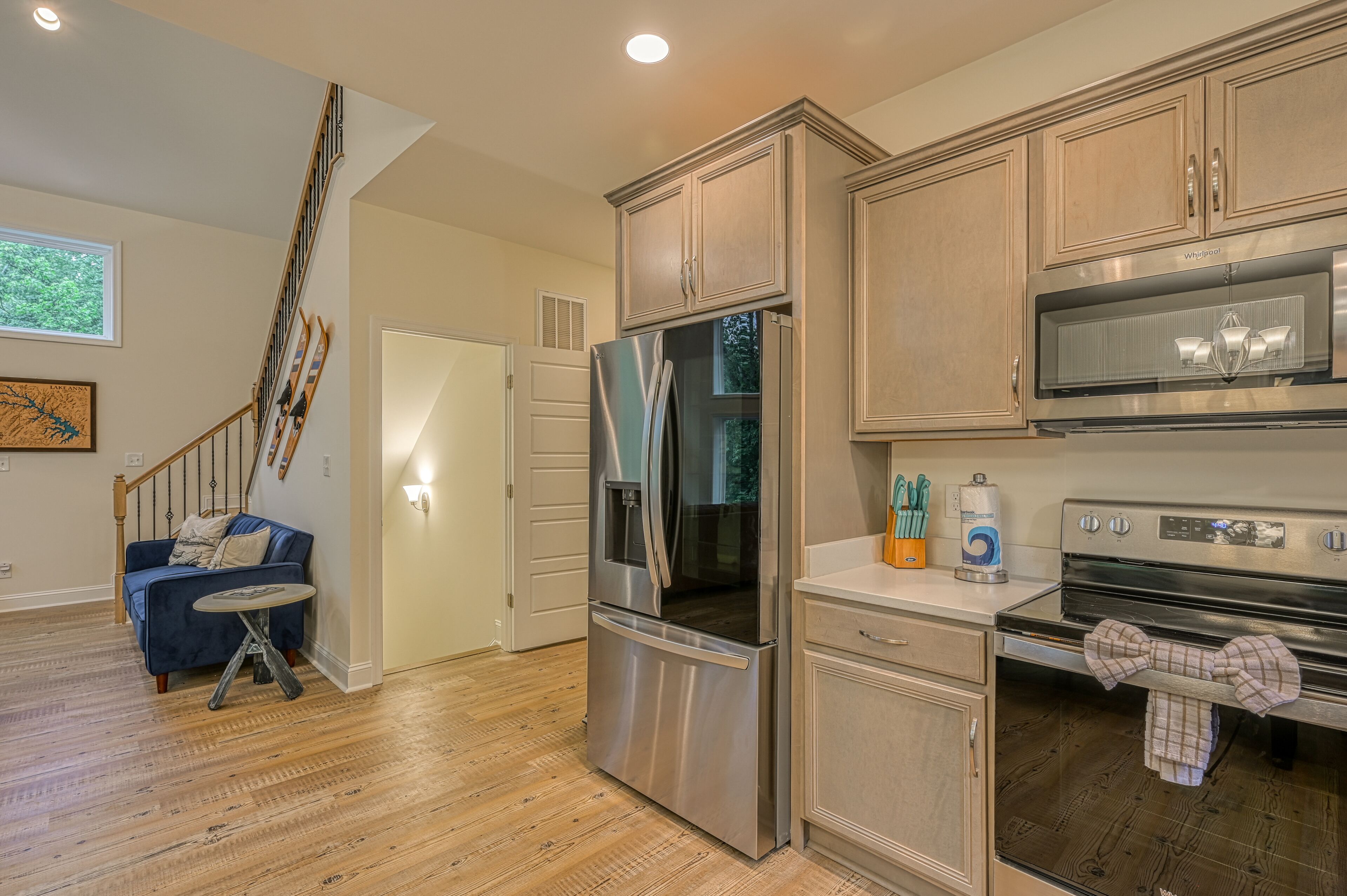 A modern kitchen with stainless steel appliances, wooden cabinets, and a staircase leading to another level.