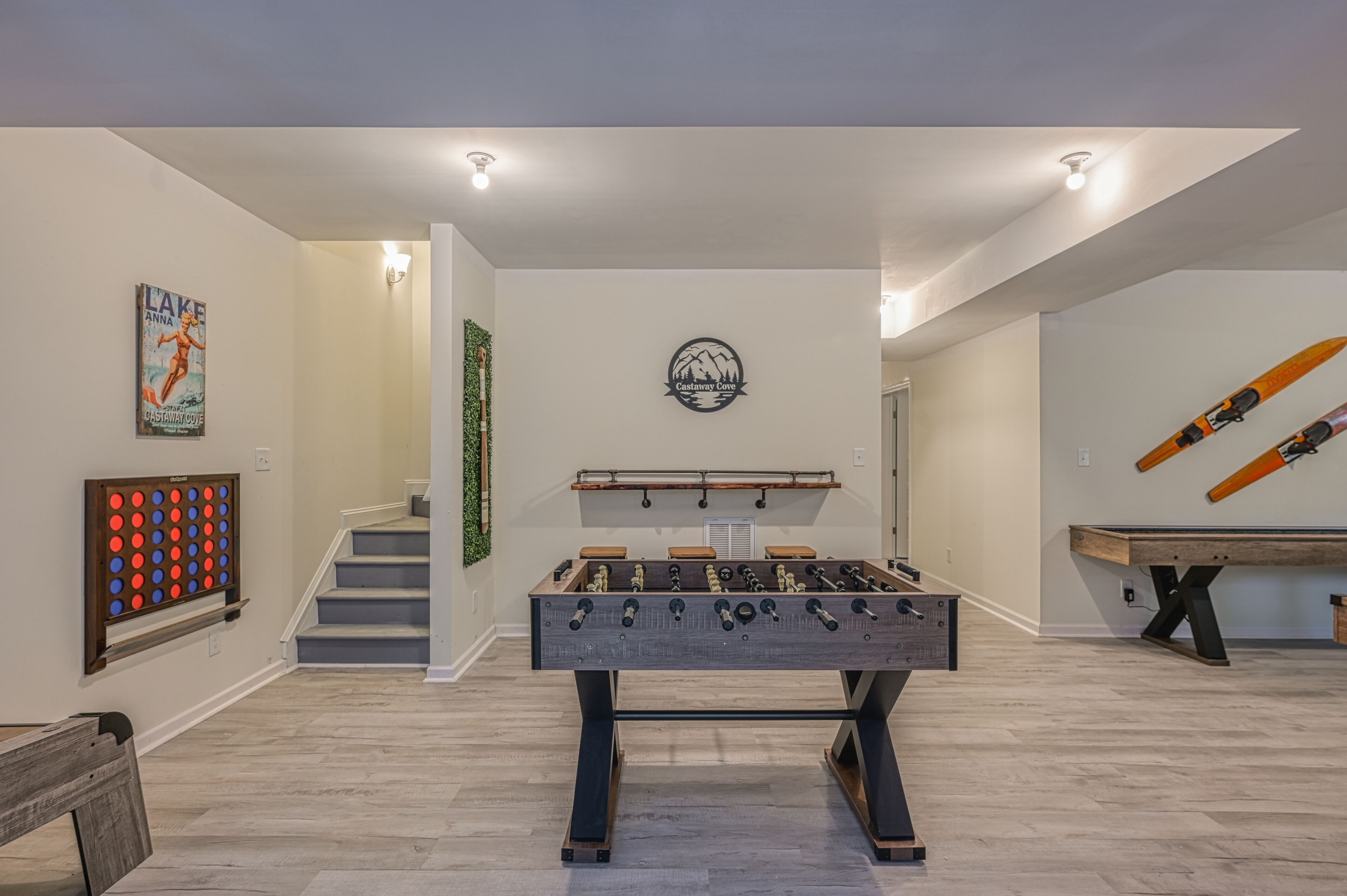 Une pièce spacieuse équipée d’un baby-foot, d’une table de billard et d’un escalier menant à un autre espace.