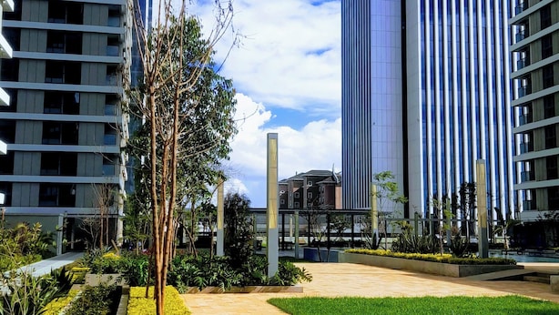 Un paysage urbain moderne caractérisé par de hauts immeubles, une promenade dallée et des espaces aménagés.