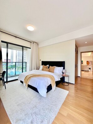 Een moderne slaapkamer met een groot bed, uitzicht op de stad en een apart zitgedeelte.