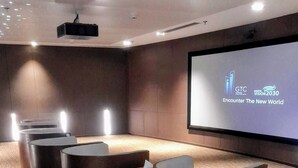 Une salle de conférence équipée d’un grand écran affichant le message « GTC Kentucky Vision 2030 : à la rencontre du nouveau monde », d’un projecteur et de plusieurs tables rondes.