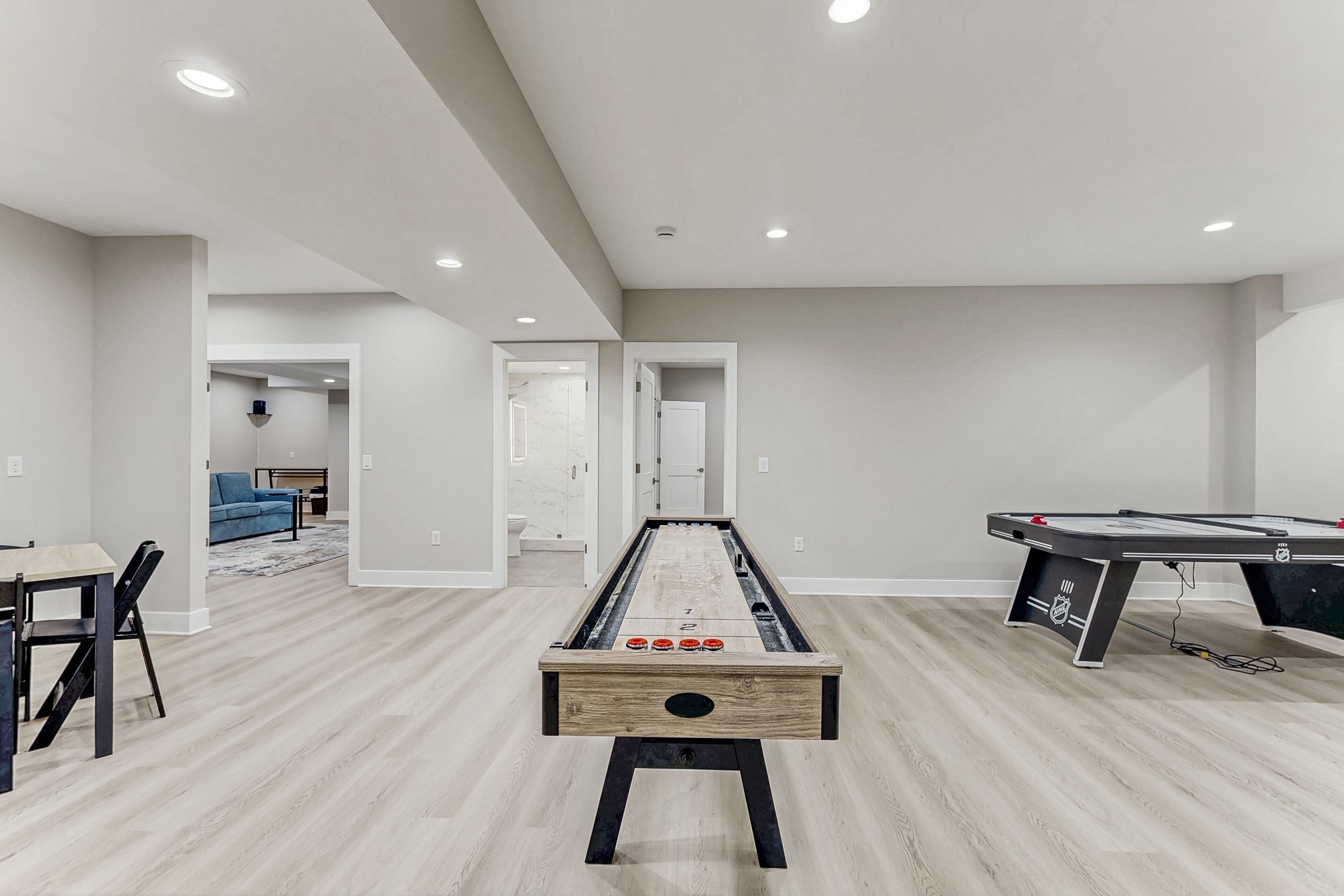 Een ruime kamer met een jeu de boules baan, een pooltafel en een eethoek met een tafel en stoelen.