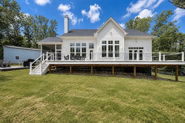 Une maison à deux étages avec une terrasse couverte, une cheminée et un garage.