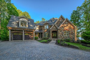A large, two-story house with a stone facade, multiple garage doors, and a well-maintained driveway. - Spacious waterfront house with private hot tub, sauna, pool table (Mineral)