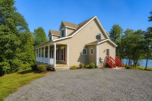 A two-story house with a covered porch, a red staircase, and a gravel driveway.