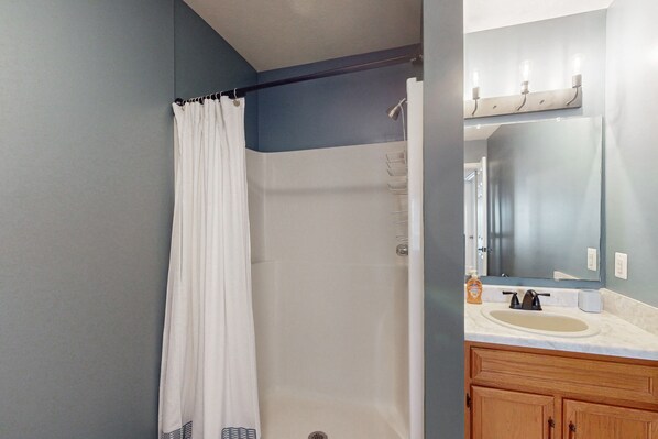 A bathroom with a shower, a sink, and a mirror.