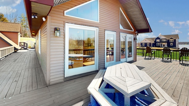 A modern house with a wooden deck, large windows, and a pool area.