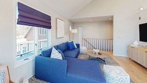 A modern living room with a sectional sofa, a round coffee table, and a view of a balcony.