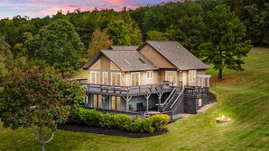 A two-story house with a deck, surrounded by a well-maintained lawn and trees.