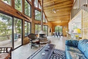 Amplia sala de estar con ventanas grandes, chimenea y un rincón de asientos acogedor.