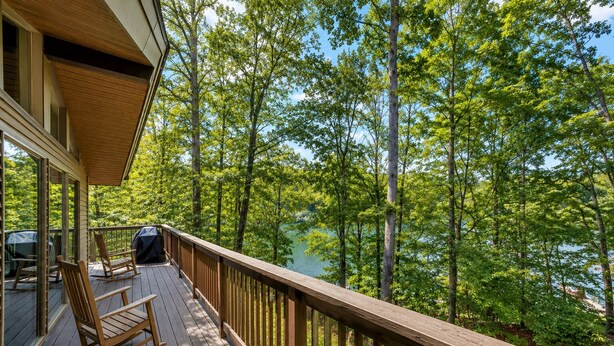 Un terrazza in legno con ringhiera che si affaccia su un lago circondato da alberi.