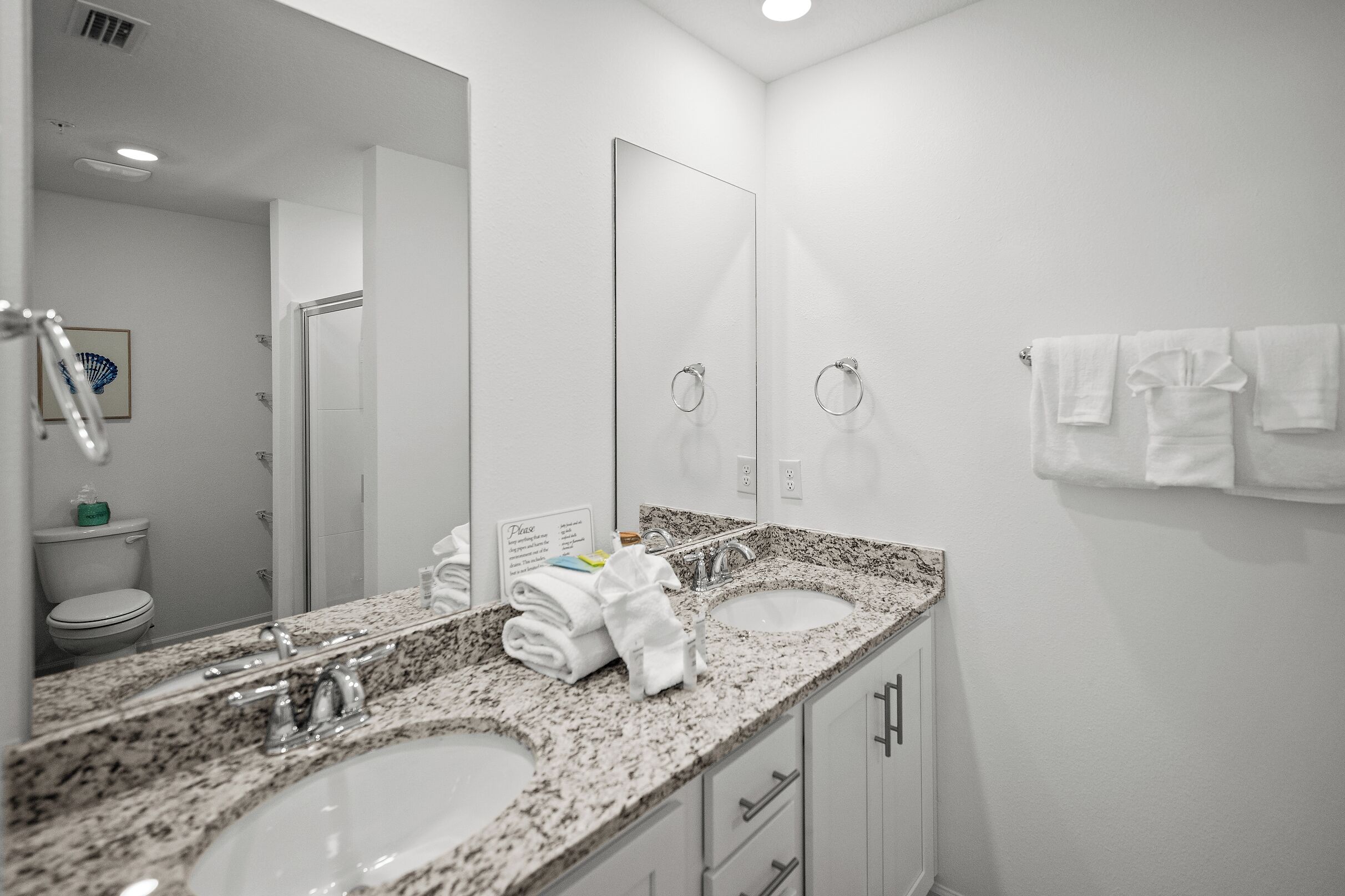 Une salle de bain moderne avec deux lavabos, un grand miroir et un porte-serviettes.