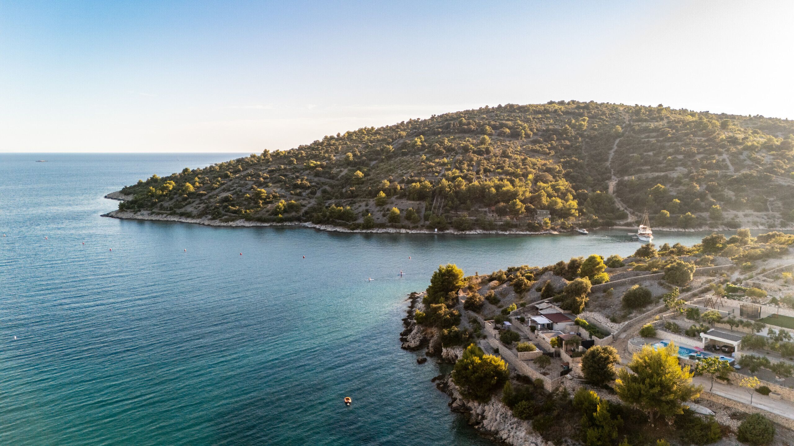 A coastal area with a small settlement, a body of water, and a boat.