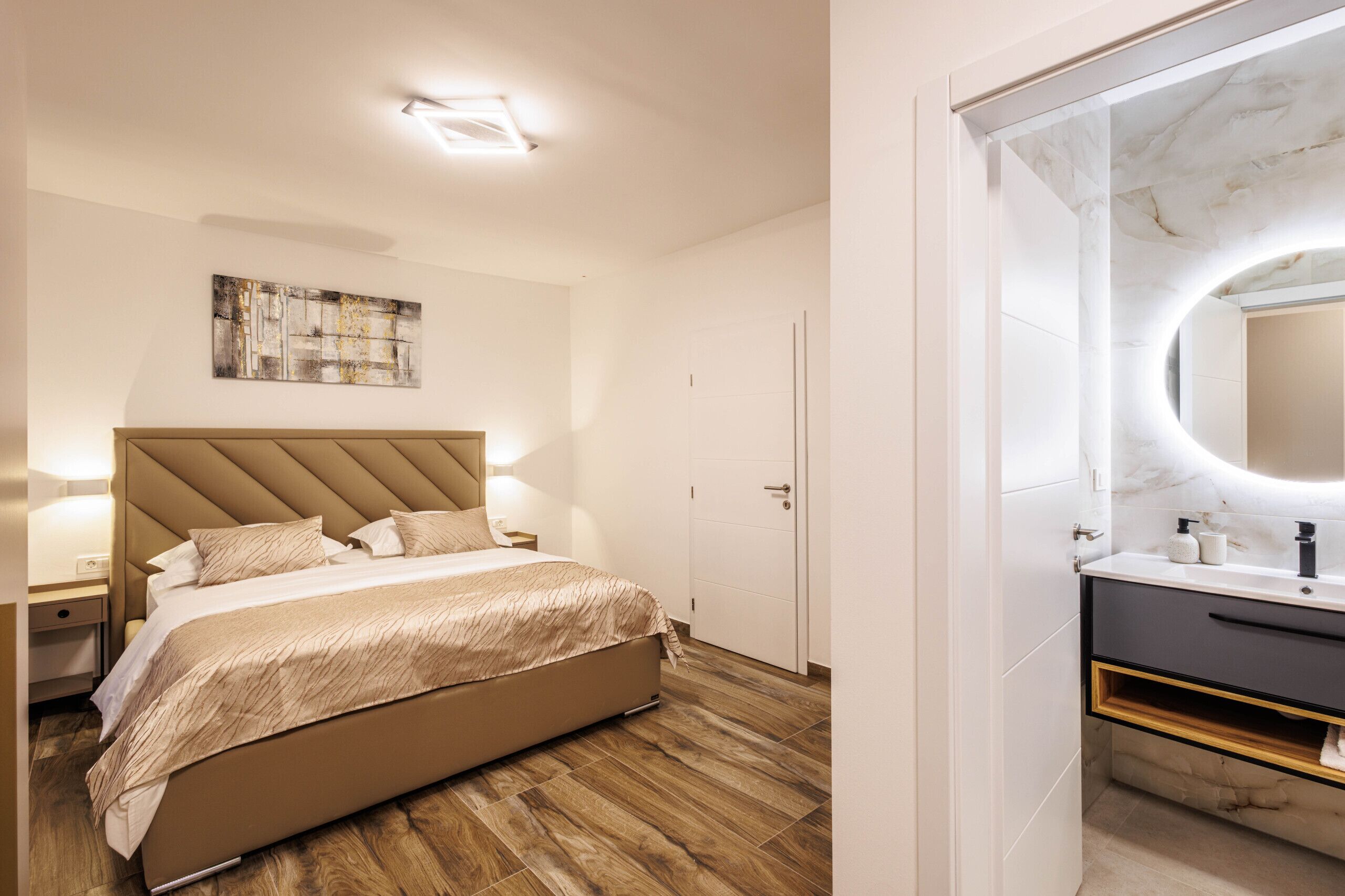 Ein modernes Schlafzimmer mit einem großen Bett, Nachttischlampen, einem Kopfteil und Holzboden.