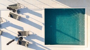 An aerial view of a swimming pool with adjacent lounge chairs and umbrellas, surrounded by a tiled deck. - Villa La Fortezza With sea View (Marina)