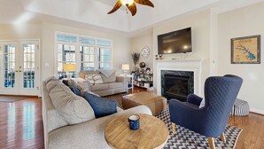 A spacious living room with a sofa, armchair, coffee table, and a fireplace. - Peaceful lakeside retreat with hot tub, private pool, dock & paddle boards (Orange)