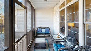 A covered porch with wicker furniture, a ceiling fan, and large windows. - Peaceful lakeside retreat with hot tub, private pool, dock & paddle boards (Orange)