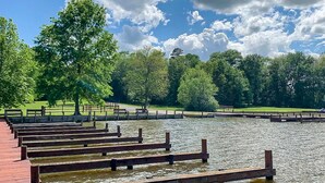 Un parc tranquil al costat d'un llac, amb bancs de fusta i un cel serè.