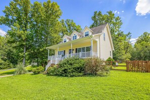 A two-story house with a porch, surrounded by a well-maintained lawn and trees.
