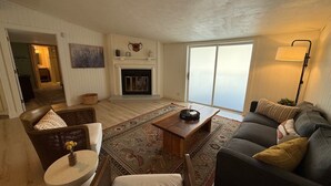 Una sala de estar con chimenea, un sofá, una mesa de centro y una lámpara.