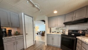 Una cocina con armarios blancos, una estufa negra y una cafetera.