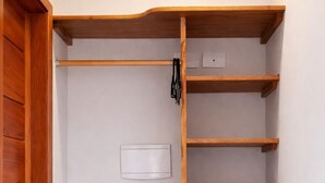 A compact room with built-in wooden shelves, a white wall-mounted thermostat, and a white refrigerator. - Swallows. Charming suite, swimming pool. Close to everything (Paraty)