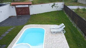 A swimming pool with a stone deck, two white lounge chairs, a small shed, and a fenced area with a tree. - Swallows. Charming suite, swimming pool. Close to everything (Paraty)