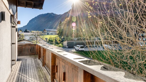 A wooden deck with a view of a mountain and a car parked in the background. - Ferienhaus Galgenul in St Gallenkirch (Sankt Gallenkirch)
