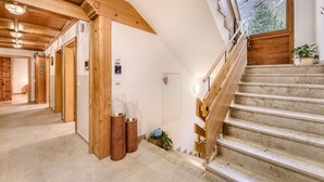 A wooden staircase with a handrail, a view of the outside through a window, and a door with a sign above it. - Ferienhaus Galgenul in St Gallenkirch (Sankt Gallenkirch)