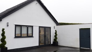 Een modern gebouw met een witte gevel, zwart gekaderde ramen, een glazen deur en een donkere garagepoort.