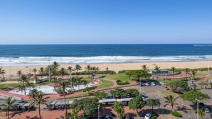 A coastal area with a beach, parking lot, and palm trees. - Durban Spa (Durban)