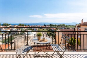 Ein Balkon mit Tisch, Stühlen und einer Topfpflanze.