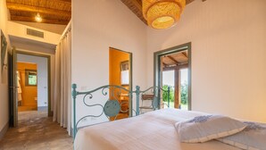 A bedroom with a bed, a window, and a door leading to another room.