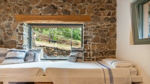 A stone-walled room with a bed, a window, and a wooden beam above the window. - La Tanca Del Conte - Suite Banano: Private Pool, Sea View, Nature Retreat (Muravera)