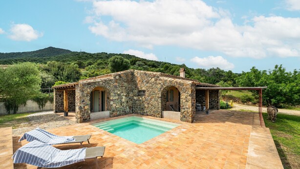 A stone building with a swimming pool, outdoor lounge chairs, and a view of a mountainous landscape. - La Tanca Del Conte - Suite Banano: Private Pool, Sea View, Nature Retreat (Muravera)